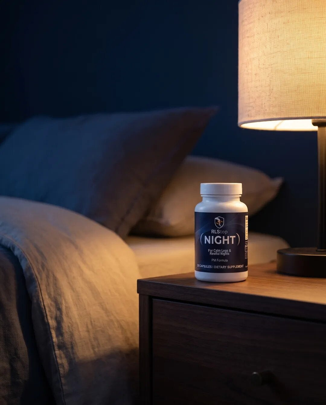 RLStop NIGHT bottle on a nightstand next to a warm bedside lamp